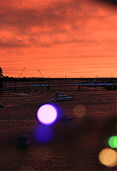 boats in harbour with lights at sunset